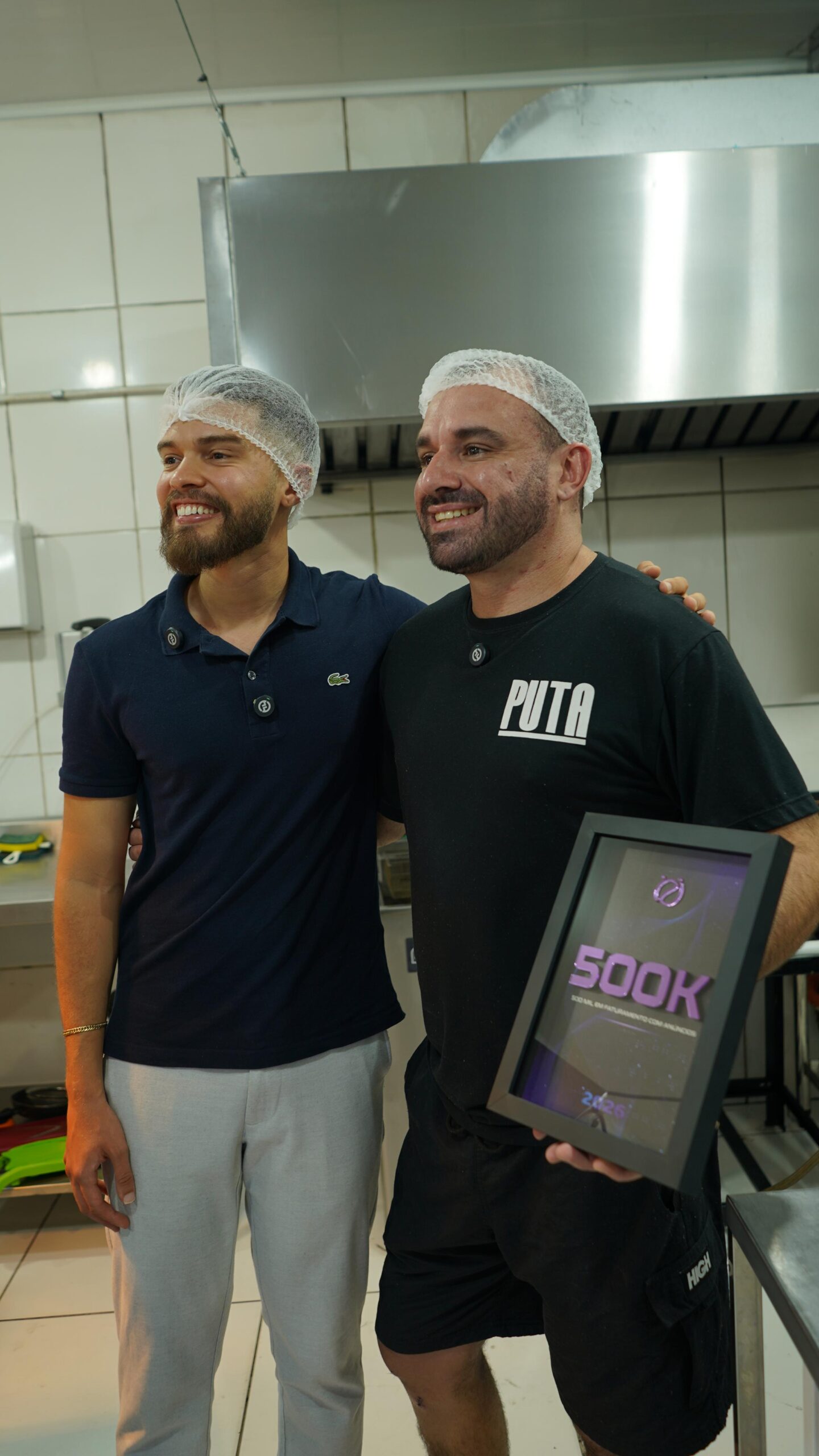 Éricles ao lado do dono da Puta Burger, segurando placa de 500 mil em faturamento com anúncios